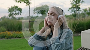 Young woman enjoys listening to music and singing while sitting in park