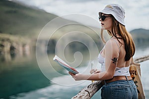 Young woman enjoys peaceful reading by a scenic lake on a sunny day