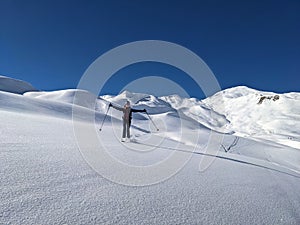 young woman enjoys the snow-covered mountain landscape with a deep snow descent in St. Antonien. Enjoy life. Skitouring