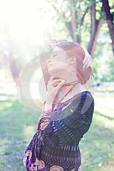 Young woman enjoys sun beams at spring park