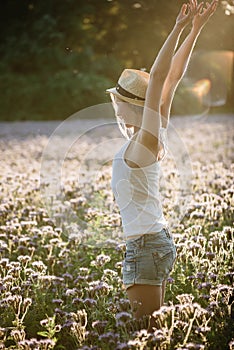 young woman enjoys sun outdoor at flower field.