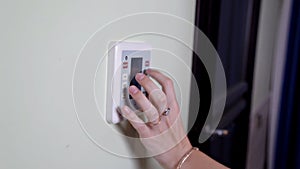 Young woman entering authorization code pin on home alarm keypad. Home security concept