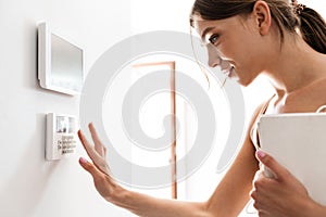 Young woman entering code of home security alarm