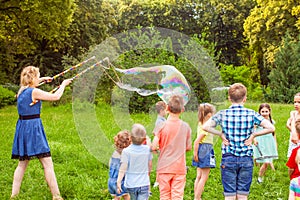 Young woman entertains children with soap bubbles