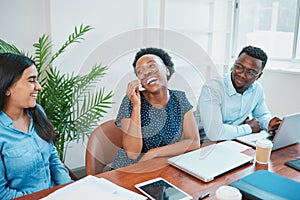 Young woman entertains her colleagues in office, pulling silly fun face laughing