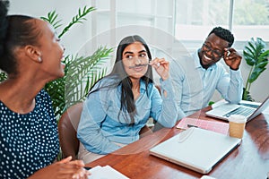 Young woman entertains her colleagues in office, pulling silly fun face laughing