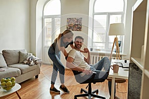 young woman entertains her husband while he is working from home