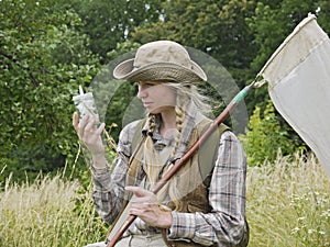 A young woman entomologist dressed in country style, with an insect net and a killing bottle.