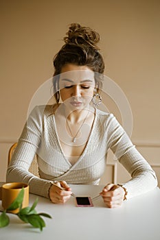 A young woman entrepreneur writes in a notebook while sitting at her desk, a master at a beauty salon takes notes, a