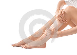 Young woman epilating her legs with wax on white background