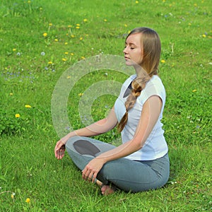 Young woman of European appearance does yoga in summer nature