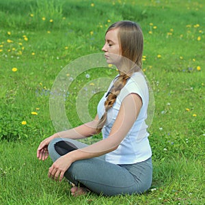 Young woman of European appearance does yoga in summer nature