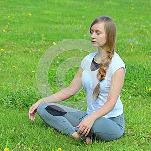 Young woman of European appearance does yoga in summer nature