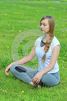 Young woman of European appearance does yoga in summer nature