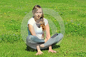 Young woman of European appearance does yoga in summer nature