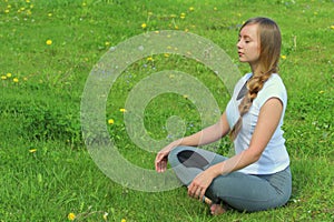 Young woman of European appearance does yoga in summer nature