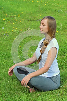 Young woman of European appearance does yoga in summer nature