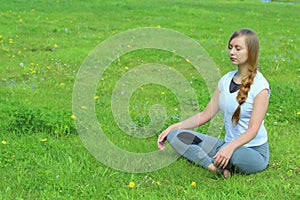 Young woman of European appearance does yoga in summer nature