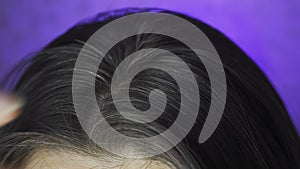 A young woman examines the gray hairs on her head. An early gray-haired girl touches her hair. macro video.