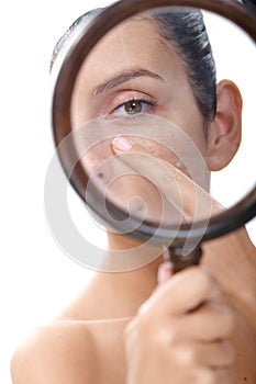 Young woman examining skin with magnifier