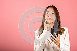 Young woman excited smiling holding mobile phone and think idea finger touch face