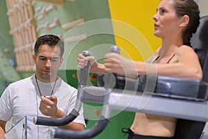 Young woman execute exercise in gym motivated by coach