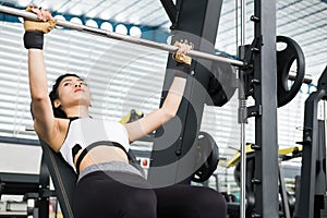 young woman execute exercise with weightlifting machine in fitness center. female athlete pump up muscle in gym. sporty girl work