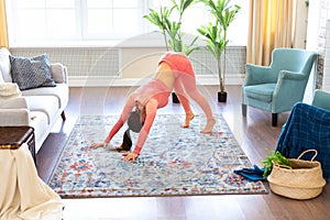 Young woman exercises at home. She is doing yoga exercise - downward dog.