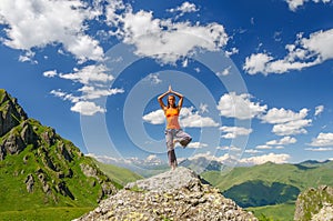 Young woman exercises yoga in the mountains