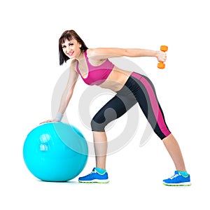 Young woman exercising with dumbbells on a fitness ball