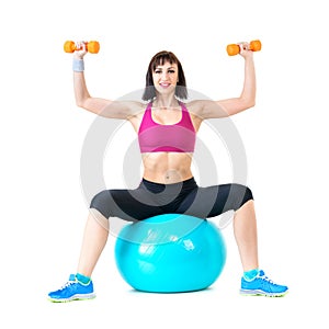 Young woman exercising with dumbbells on a fitness ball