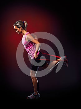 Young woman exercising with elastic fitness band in the gym