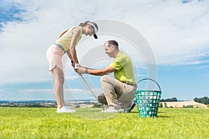Young woman exercising the golf swing helped by her instructor photo