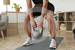 Young woman exercising with kettlebell at home, closeup
