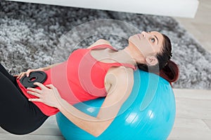 Young woman exercising on pilates ball with weights