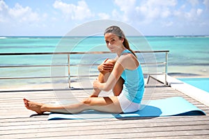 Young woman exercising by pool and beach