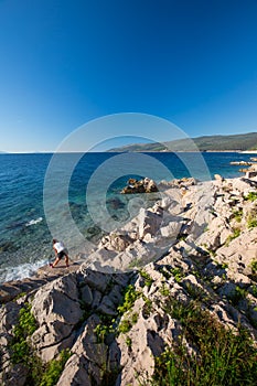 Young woman exercising by sunrise on the stone crystal clear tourquise sea in Croatia, Europe photo