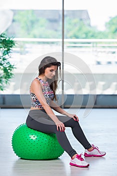 The young woman exercising with swiss ball in health concept