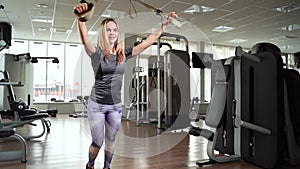 Young woman exercising workout using fitness straps TRX in the gym.