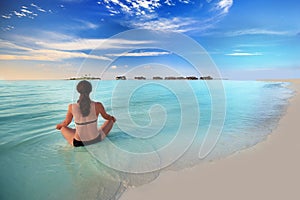 Young woman exercising yoga on tropical island