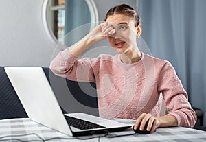 Young woman experiencing eye pain after working on laptop