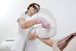 Young woman experiencing laser hair removal for her arms in a salon setting