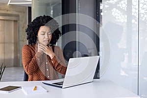 Young woman experiencing a sore throat while working in office
