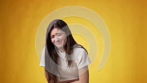 Young woman experiencing stomach pain against yellow background