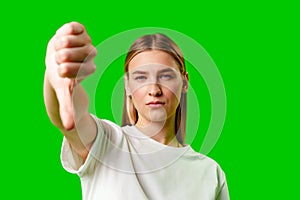 Young Woman Expressing Disapproval With a Thumbs Down Gesture Against a Green Background