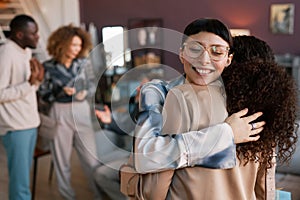 Young woman in eyeglasses embracing her friend after giving her bithday present