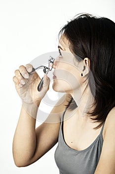 Young woman with eyelash curler on white