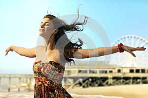 Young woman eyes closed arms wide open at beach