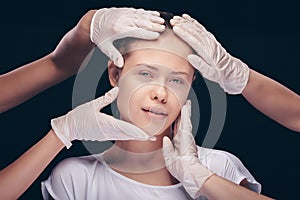 Young woman with eyes closed having an medical exam of her face skin by plastic doctors