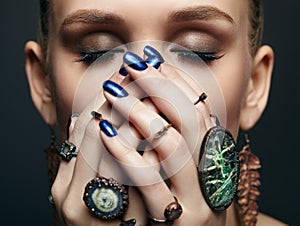 Young woman with eyes closed and many bijouterie rings with stones on fingers